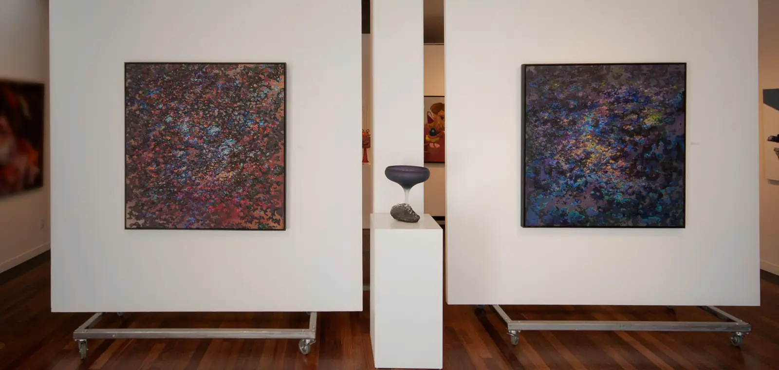 Two abstract paintings displayed on freestanding white walls