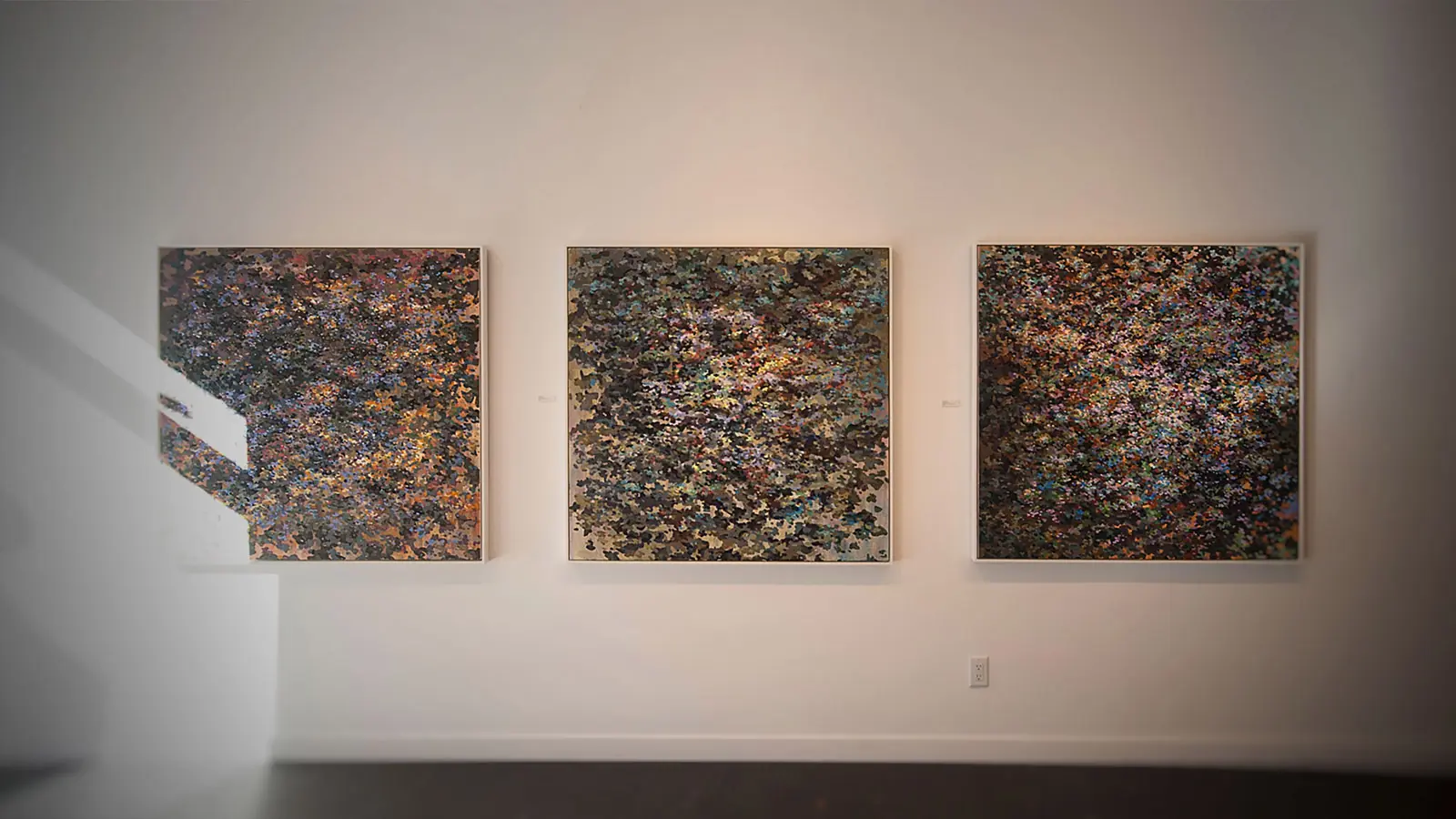 Three abstract paintings installed together on a white gallery wall