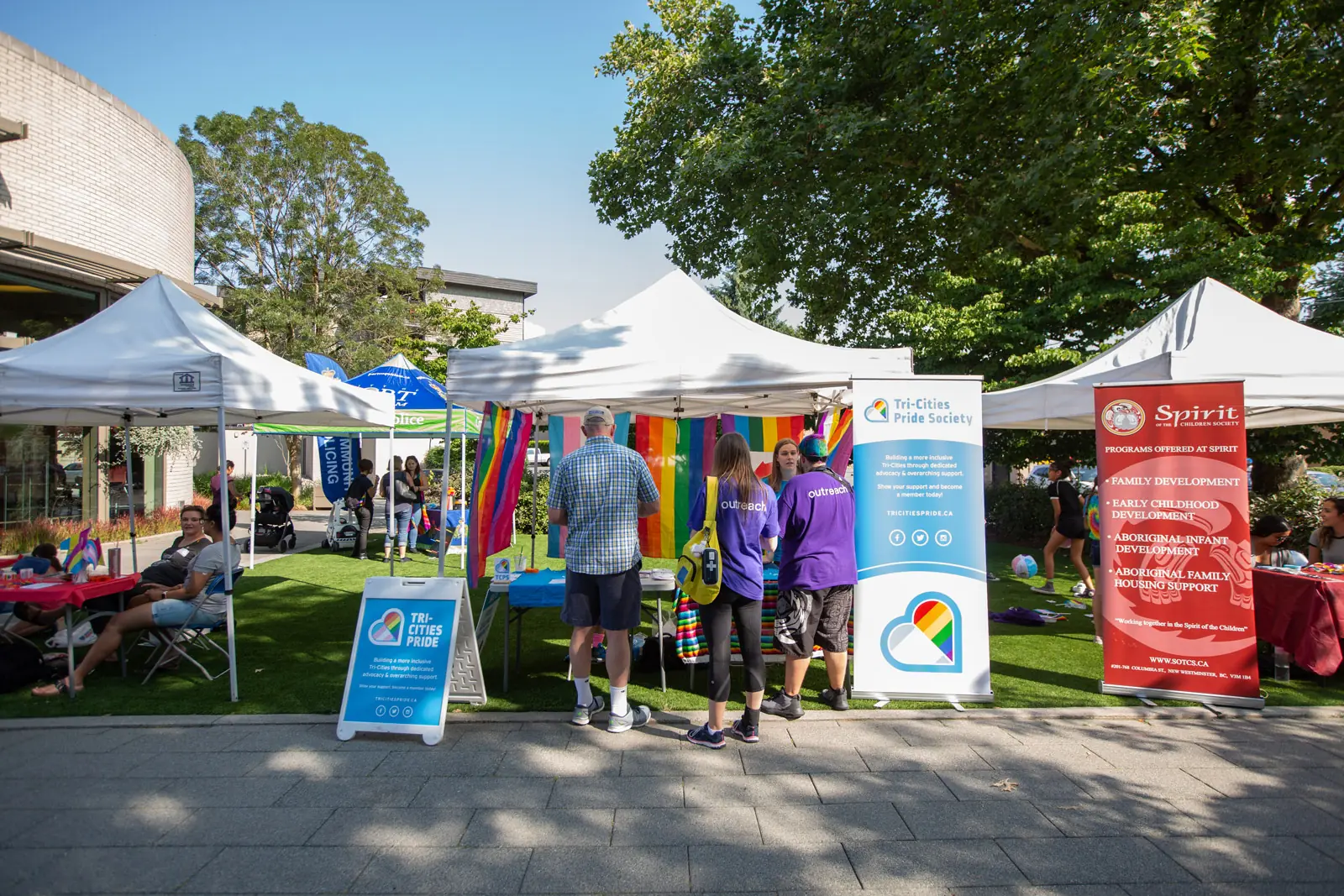 Community event tents and Pride banners beside the public work