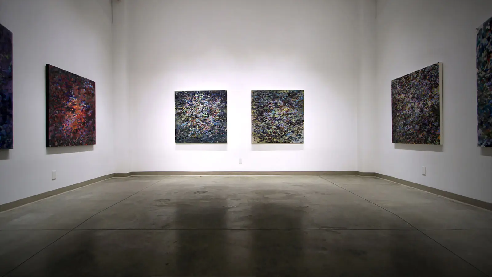 Abstract paintings installed across the walls of a gallery