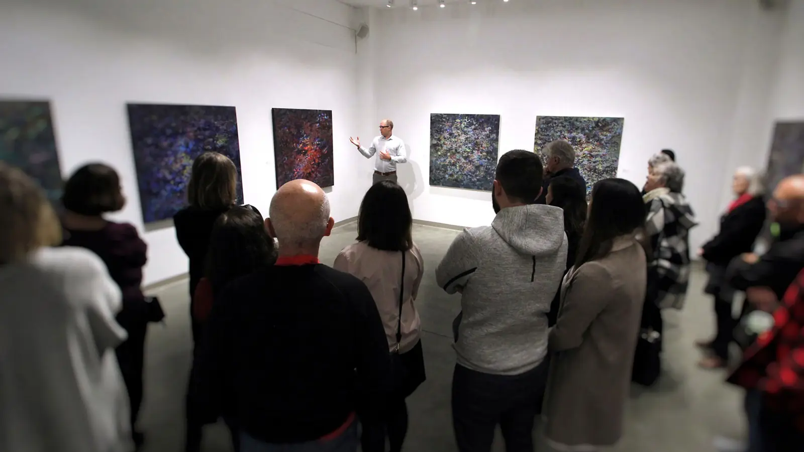 Visitors gathered for a talk among the installed paintings