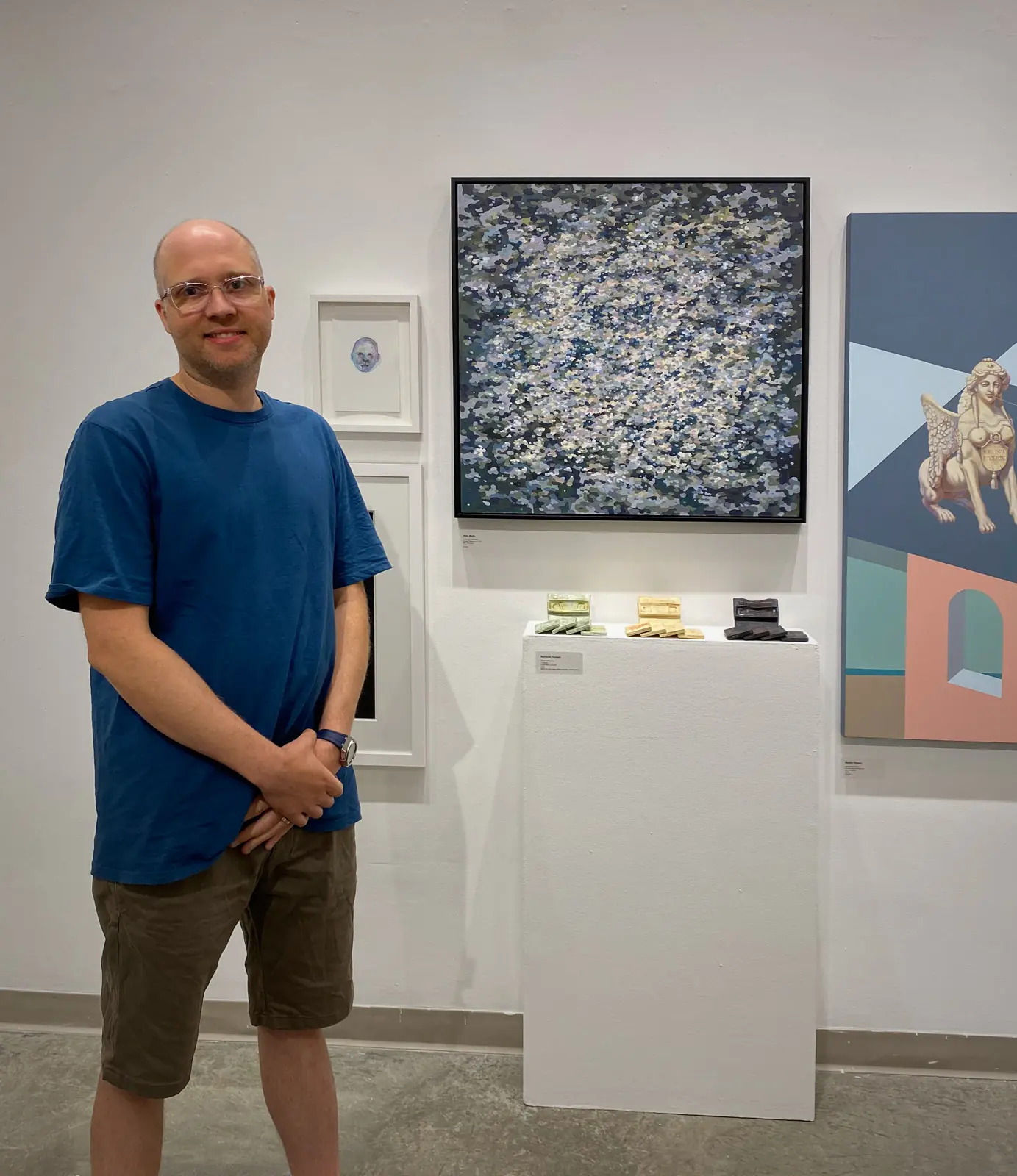 Artist standing beside an abstract painting in the gallery